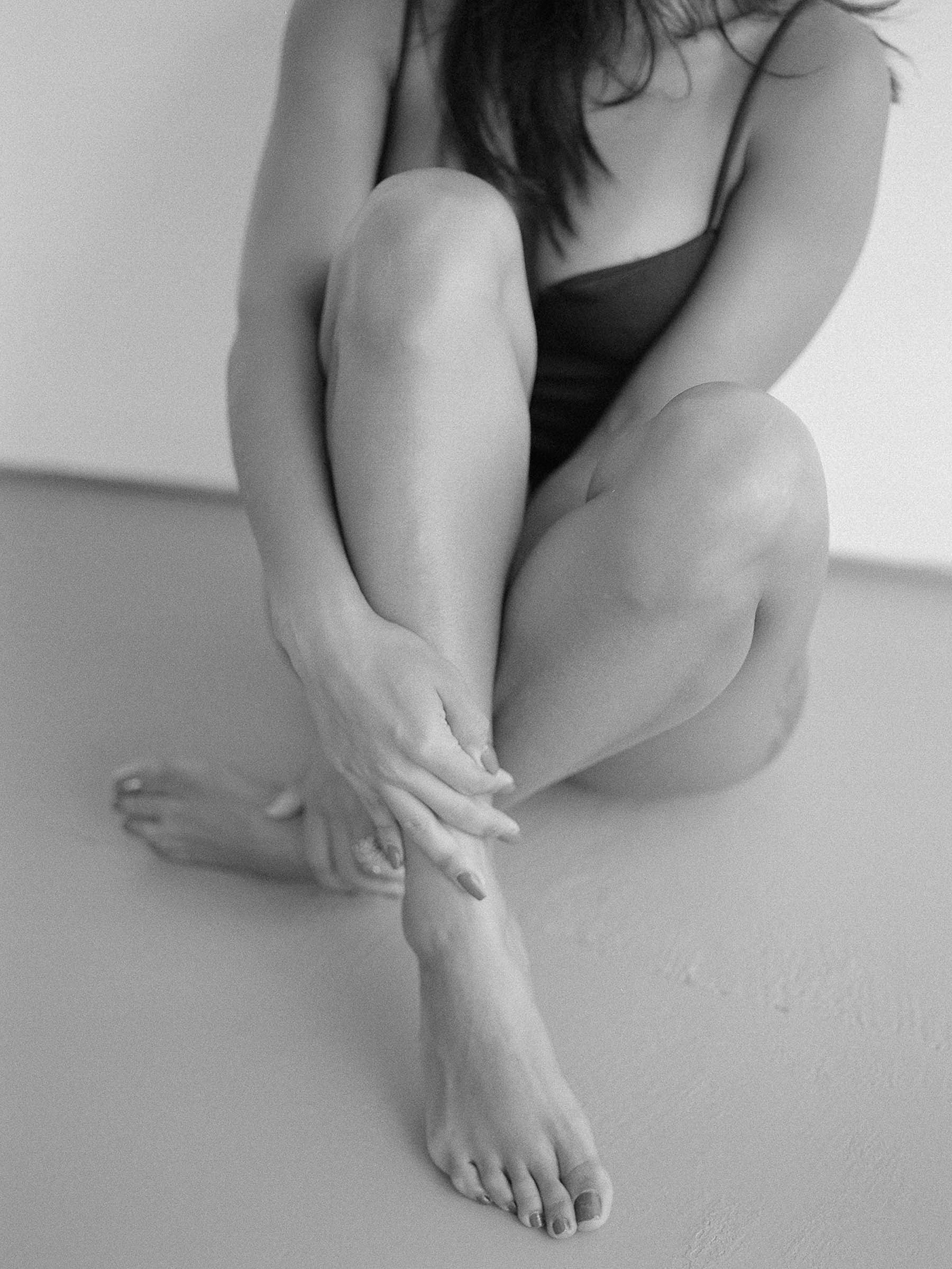 black and white picture of woman sitting on the floor holding her leg